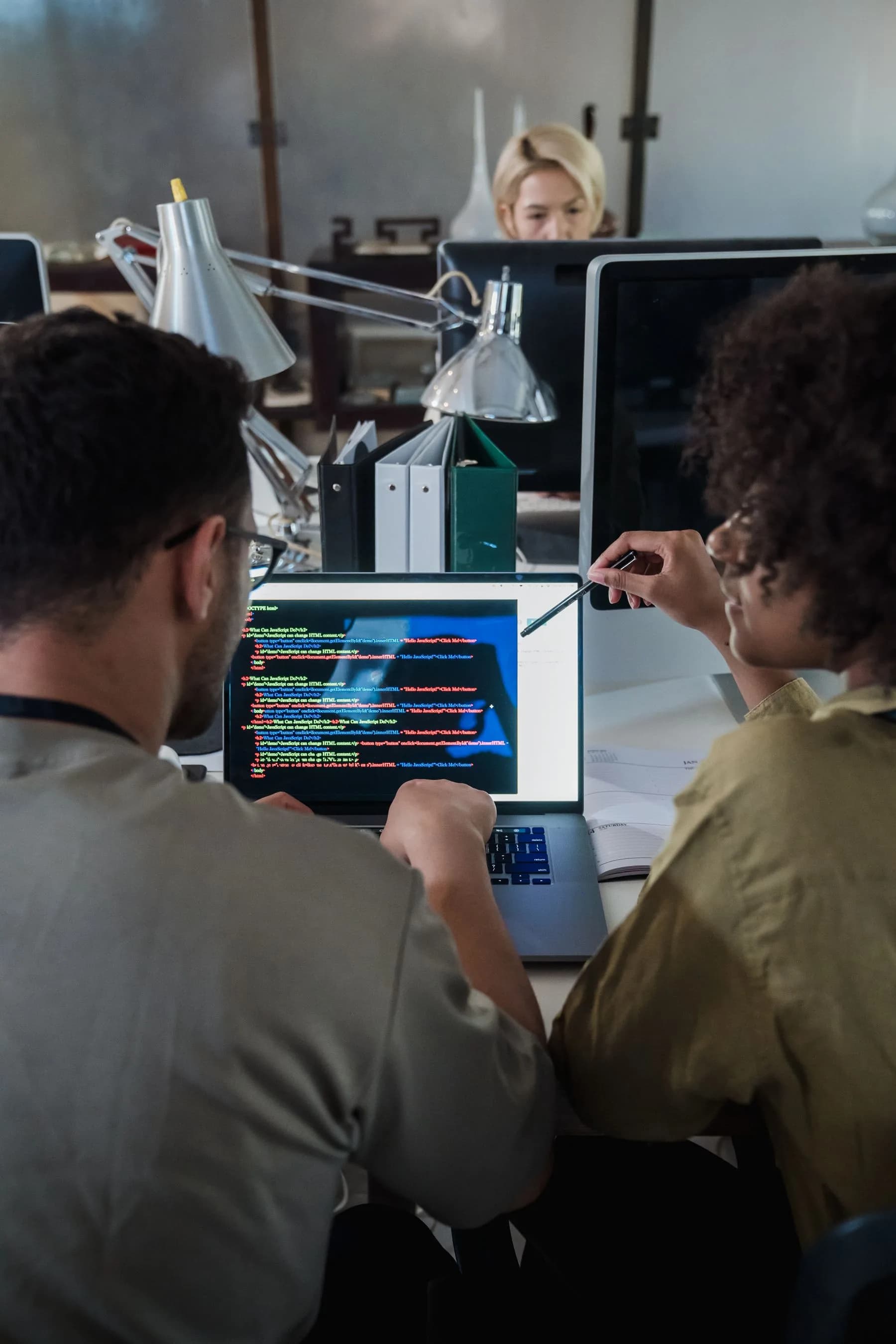 Dos personas revisando y comentando código en una pantalla